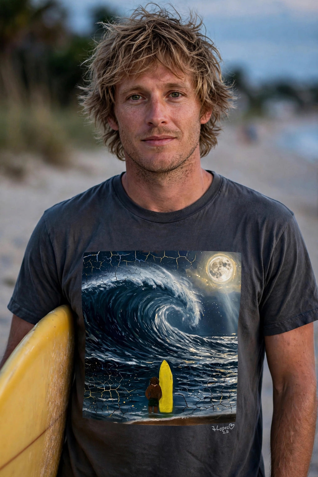 Man wearing the Surfer's Moon art print t-shirt holding a surfboard on the beach at dusk